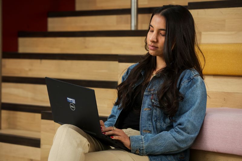 female student sitting with laptop on staircase in One Elmwood